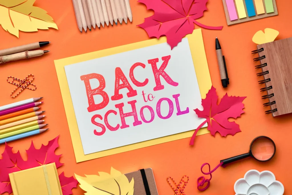 Back to School paper card surrounded by pencils, notebooks, and autumn leaves