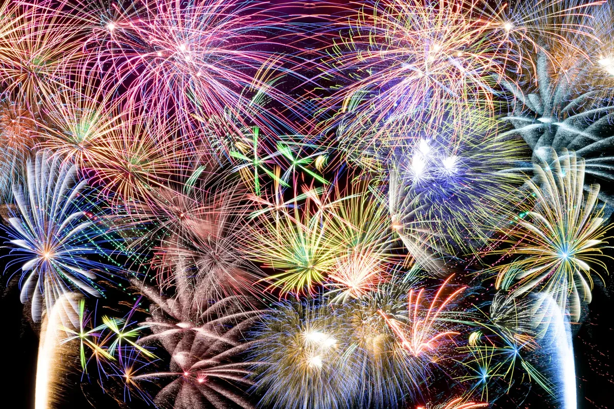 Colorful fireworks bursting over a night sky at a New Year's Eve celebration