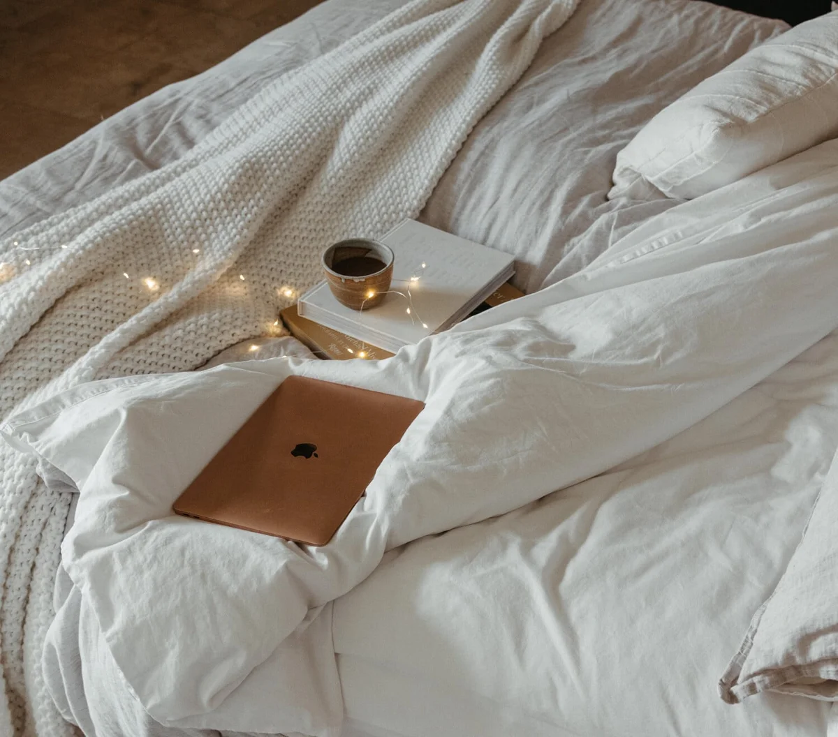 Cozy bed with laptop, books, and coffee for a fall movie night