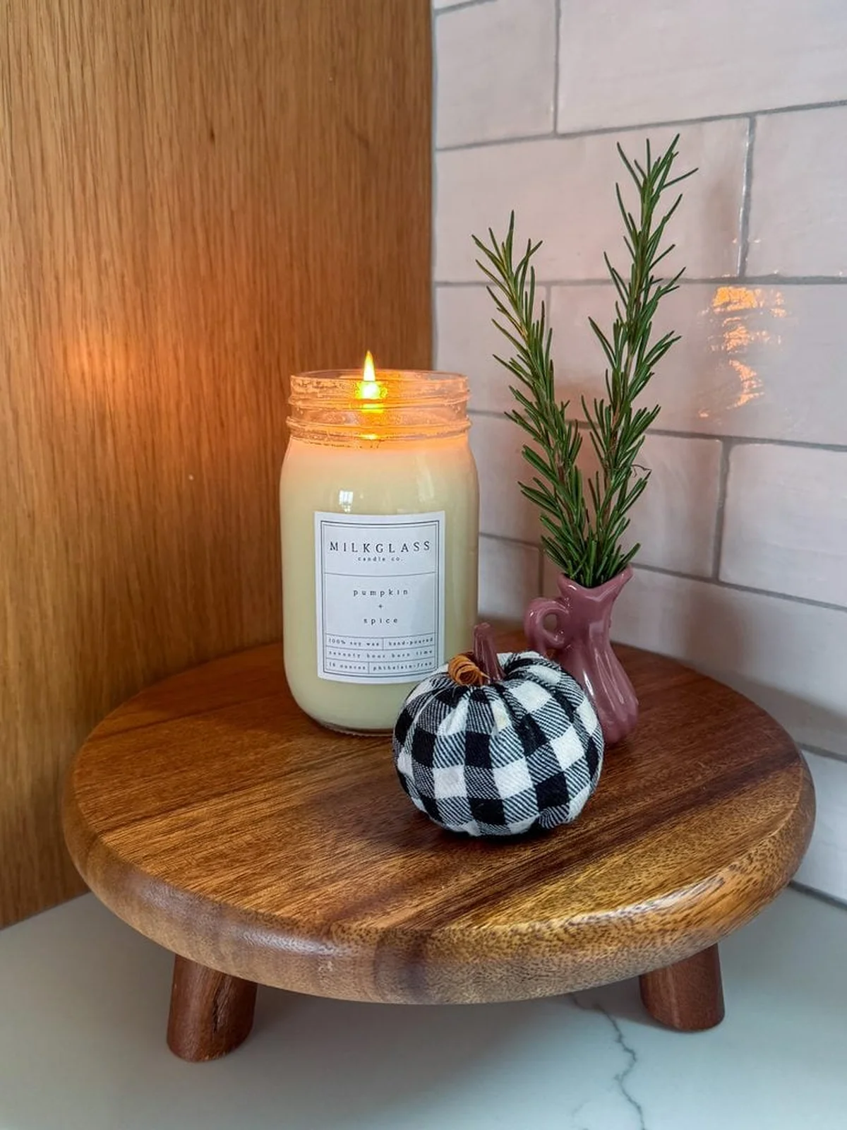 lit pumpkin spice candle beside a checkered pumpkin
