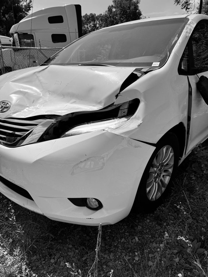 Front view of crumpled damaged Toyota minivan at tow yard