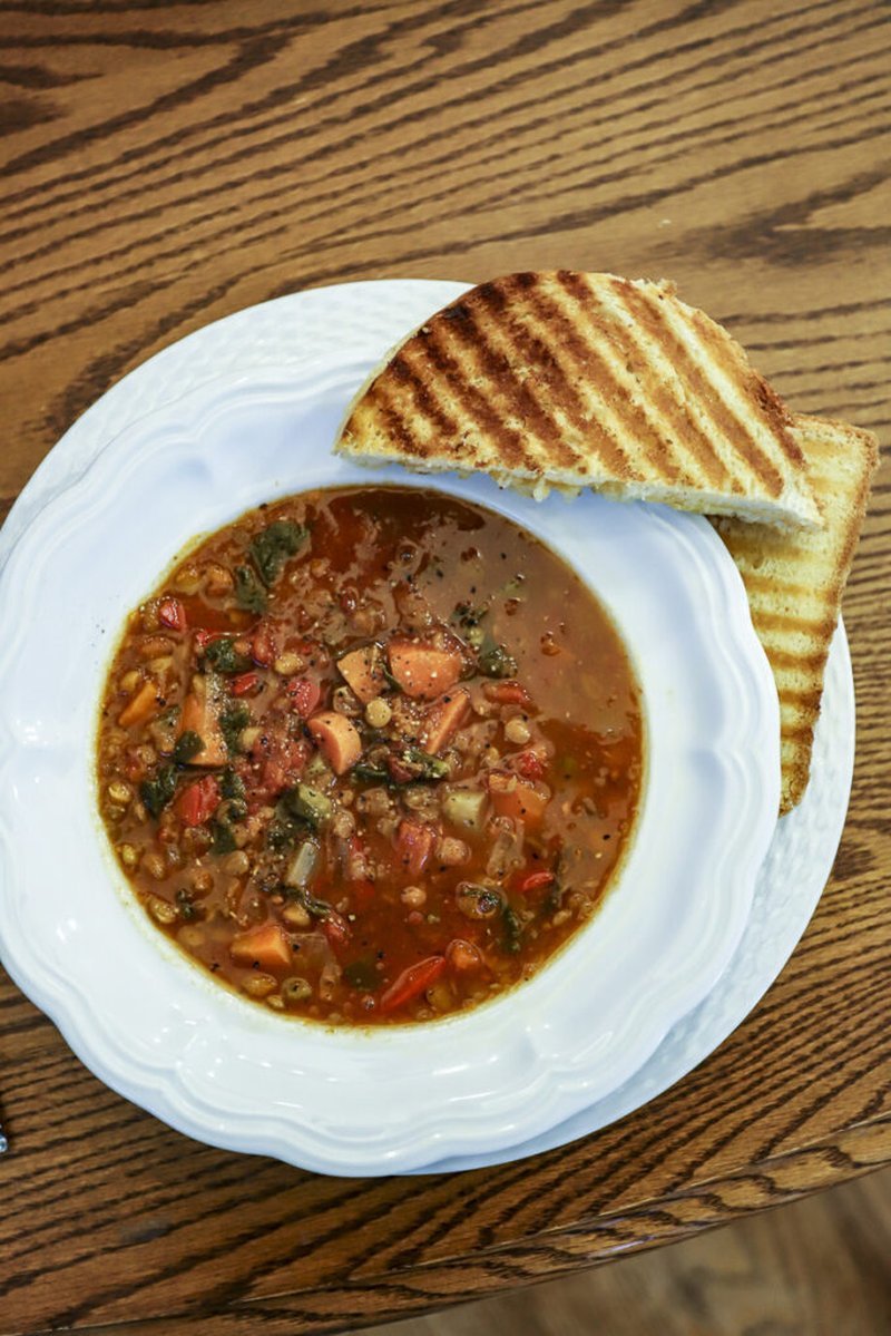 bowl of vegetable soup with grilled cheese bread on a wooden table
